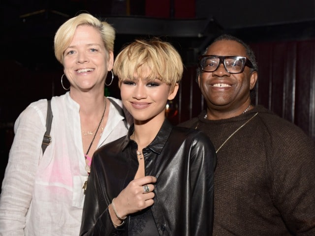 Zendaya in a black jacket with her father in a dark chocolaty t-shirt and her mother in a white dress.